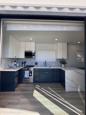 A modern kitchen with white cabinets, a built-in oven, and a large island with a sink. - Charming 1-bedroom casita in peaceful Mesa with pickleball sports court. (Mesa)