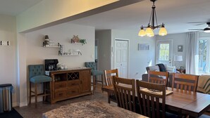 A spacious kitchen with a granite countertop, wooden cabinets, and a dining area with a table and chairs. - Riverside Landing Cottage (Alberton)