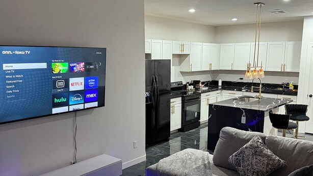 A modern living room with a flat-screen TV mounted on the wall, a sofa, and a coffee table.