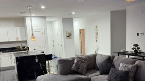 A modern living room with a sectional sofa, a coffee table, and a black marble fireplace.