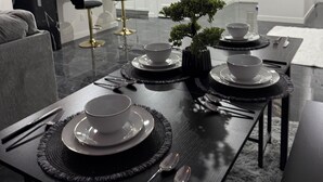 A modern dining area with a black table set for four, white plates, and a small potted plant.