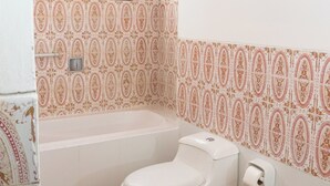 A bathroom with a white toilet, a white sink, a white bathtub, and a white trash bin. - Hawka (Ica)