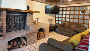 Ein gemütliches Wohnzimmer mit Kamin, einem an der Wand montierten Fernseher und einer bequemen Couch.