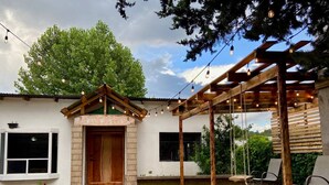Eine überdachte Terrasse mit einer Holz-Pergola, einer Schaukel und einer Sitzecke.