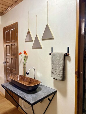 Experience the rustic charm of this bathroom, featuring a unique vessel sink and minimalist wall decorations.