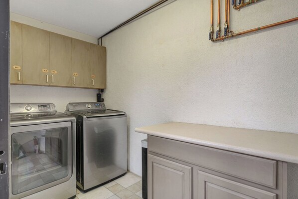 A compact kitchen with stainless steel appliances, wooden cabinets, and a white countertop.