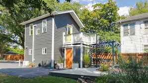 A two-story house with a front porch, a wooden deck, and a fenced yard. - Colorful private guesthouse in charming Richmond with Parking (Richmond)
