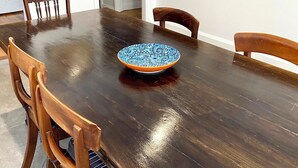 A dining room with a wooden table, four chairs, a decorative bowl, and two framed artworks on the walls. - The Merchant's Nook (Armidale)