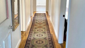A hallway with a patterned rug, white doors, and a hanging light fixture. - The Merchant's Nook (Armidale)