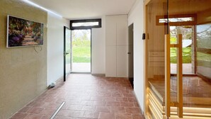 A hallway with a tiled floor, a painting on the wall, and a door leading outside. - Cozy apartment in Montemonaco (Montemonaco)