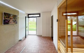A hallway with a tiled floor, a painting on the wall, and a door leading outside.