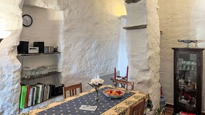 A dining area with a table set for two, a bookshelf, a clock, and a cabinet with glassware. - Vacation home Paola by Interhome (Valloria)