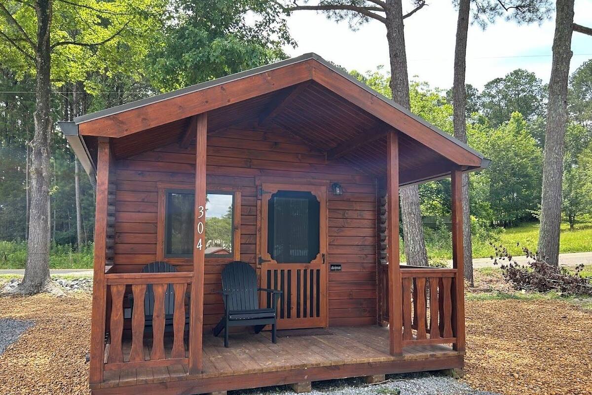 A wooden cabin with a porch, a door, and a window.
