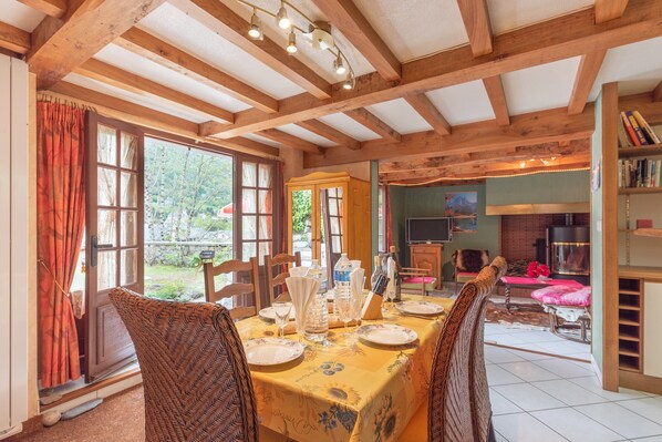 Un comedor con techo de madera, ventanas amplias y una mesa dispuesta para cuatro.