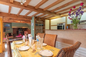 A dining area with a wooden ceiling, a table set for two, and a vase with flowers on the wall.
