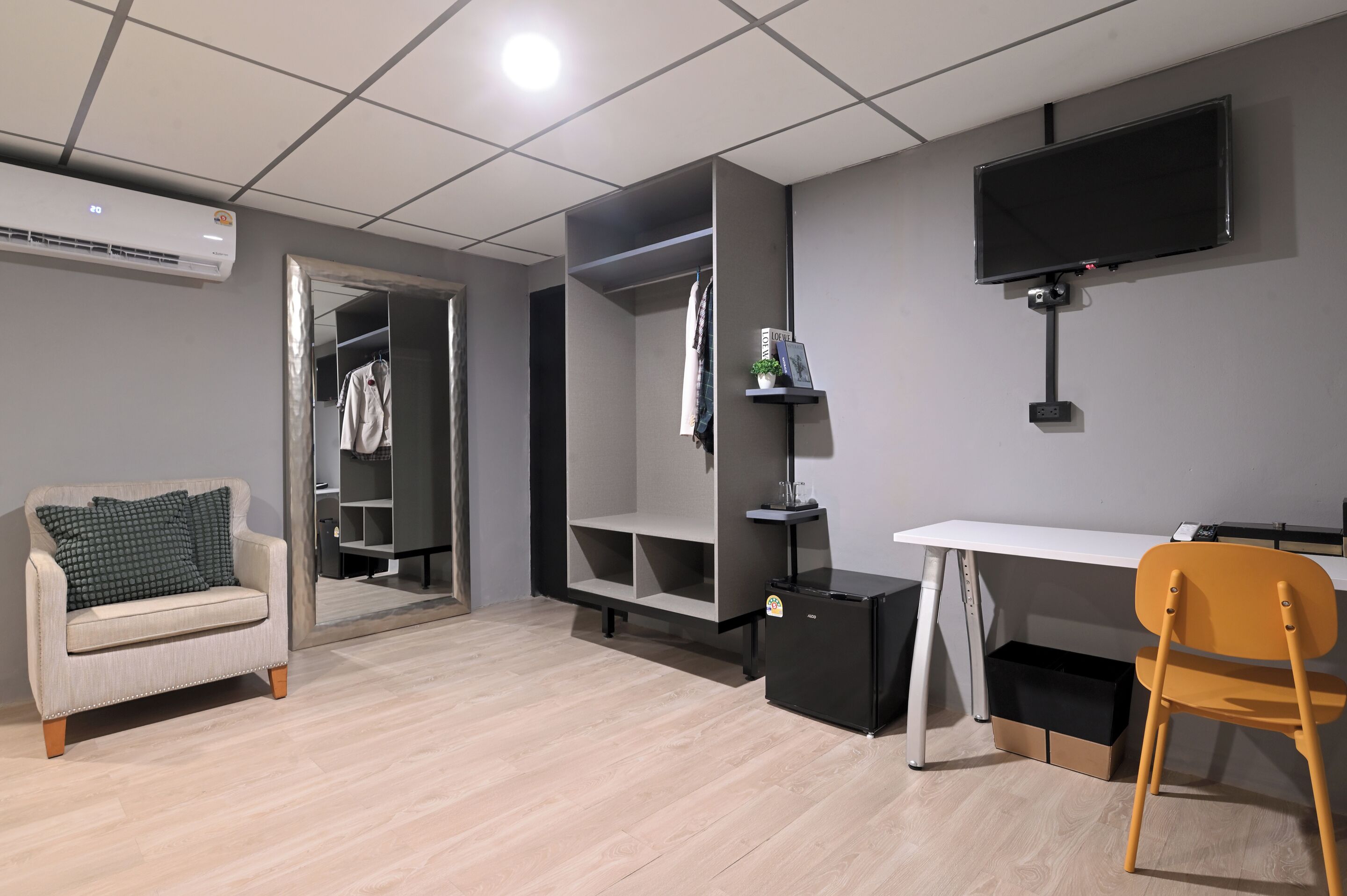 A modern room with a sofa, a desk, a TV, a wardrobe, and a small black cabinet.