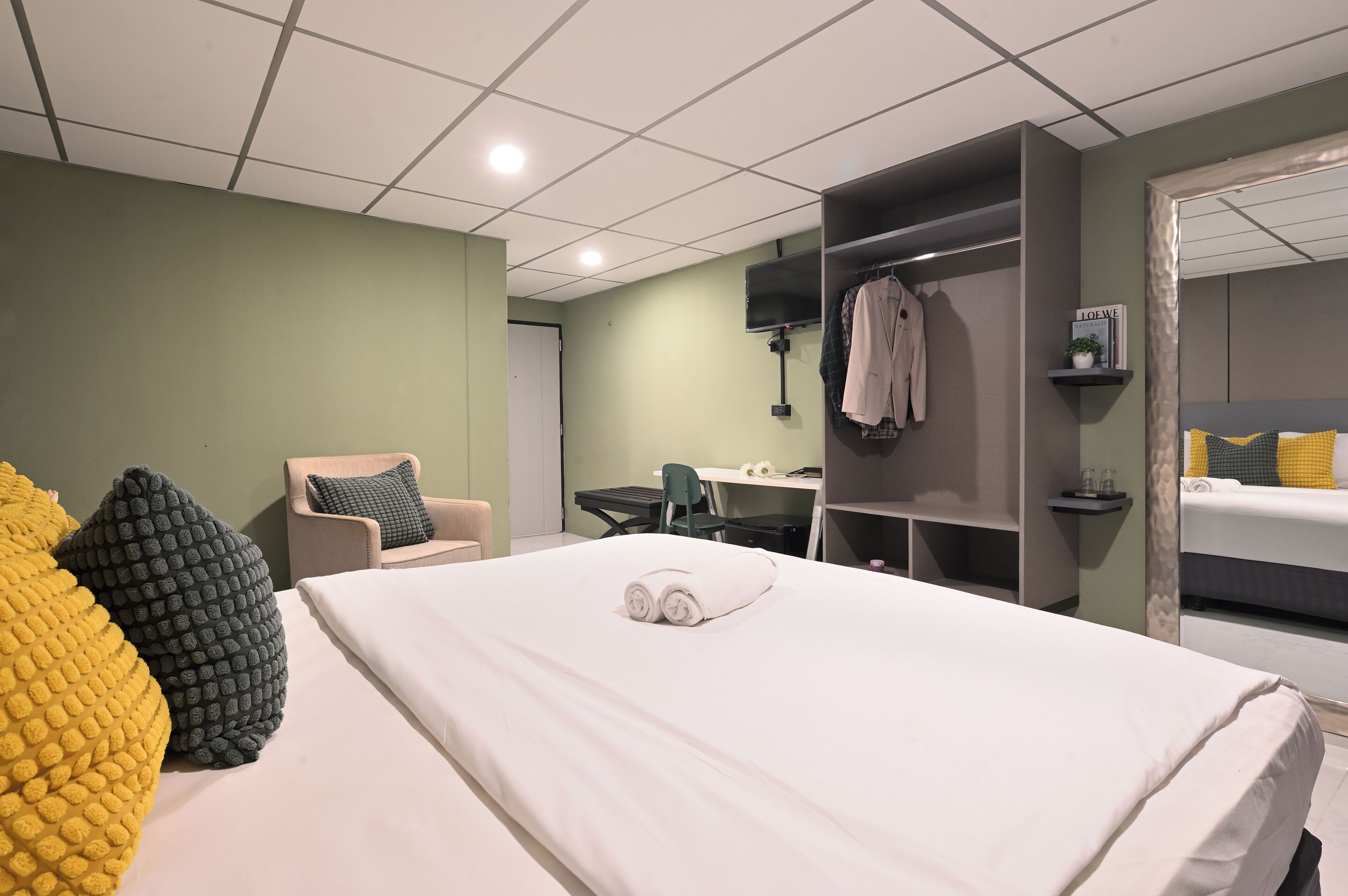 Une chambre d’hôtel avec un lit, un bureau, une chaise et une armoire.