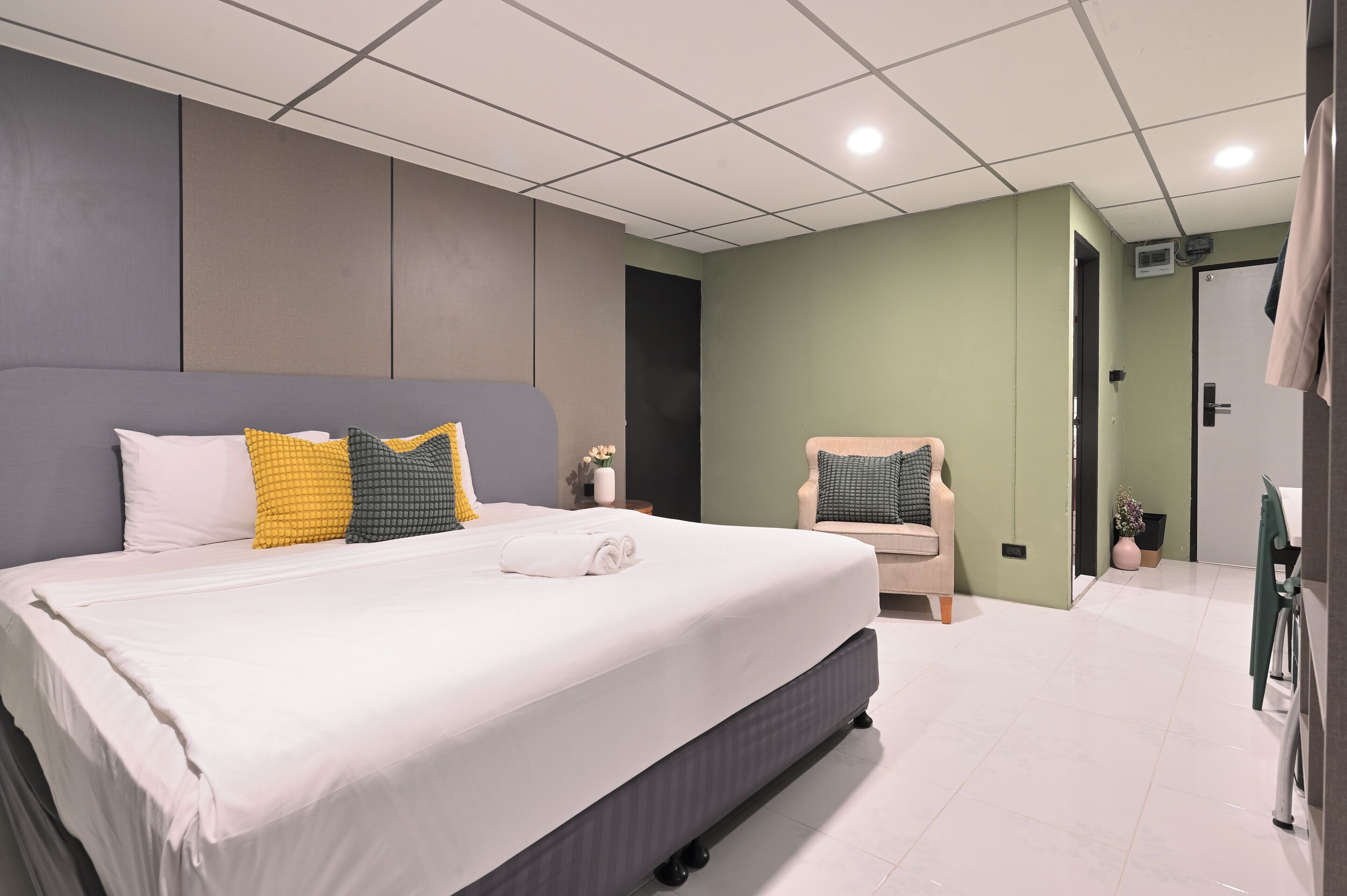 A modern hotel room with a large bed, a chair, and a small table.