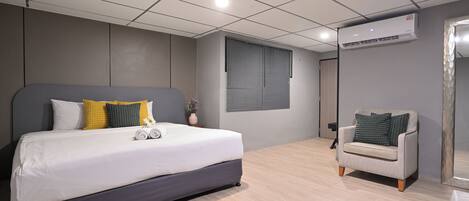 Un dormitorio moderno con una cama grande, un sofá gris y una ventana con persianas.