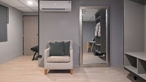 A modern room with a grey sofa, a large mirror, and a wardrobe.