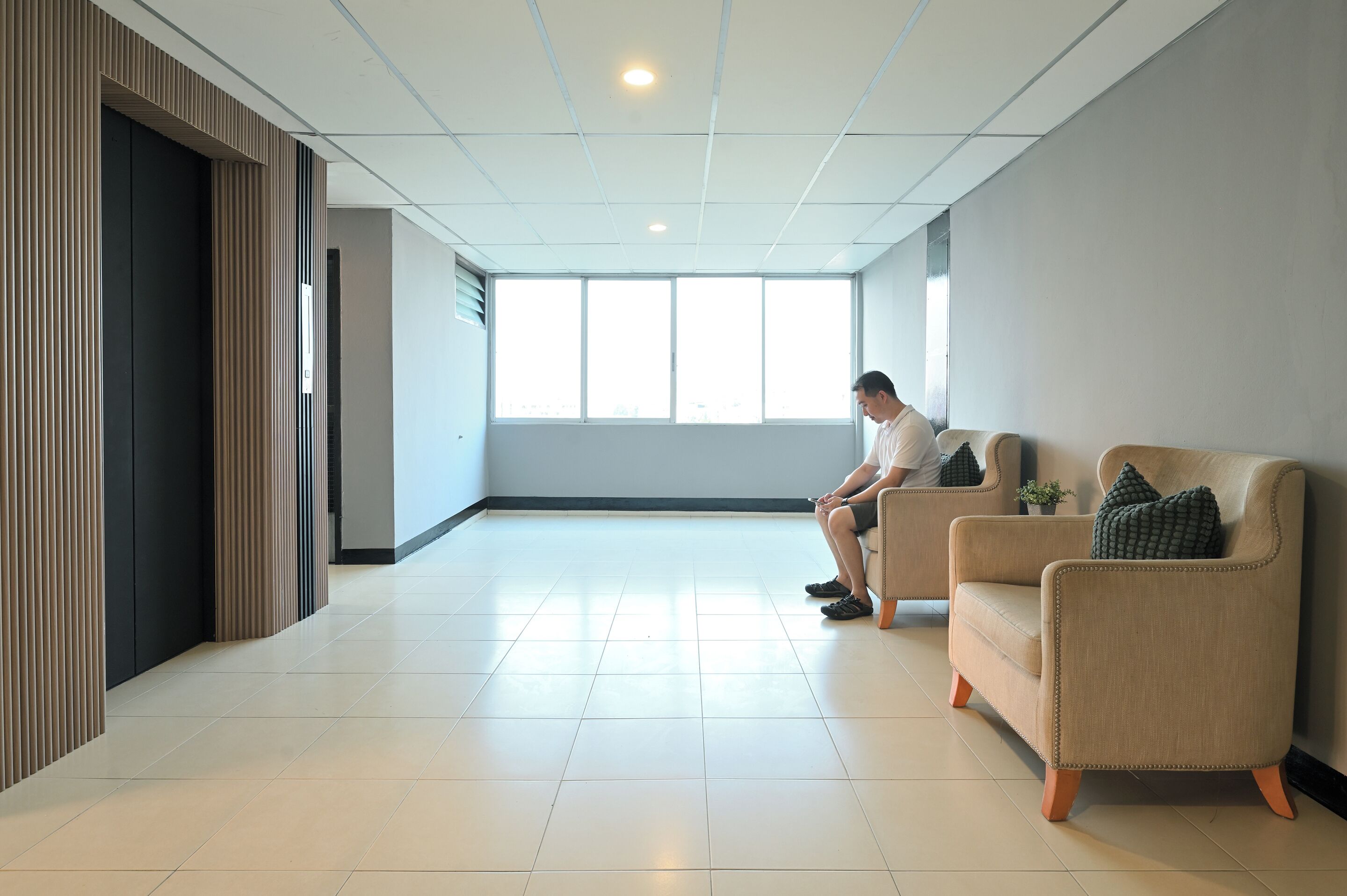 A modern waiting area with a large window, a sofa, and a person sitting.