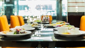A dining area with a long table set for multiple guests, featuring various dishes and a clear view of the restaurant's interior.