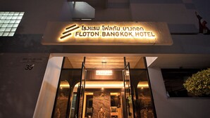 The exterior of the Flotton Bangkok Hotel with a modern design, illuminated sign, and entrance with glass doors.