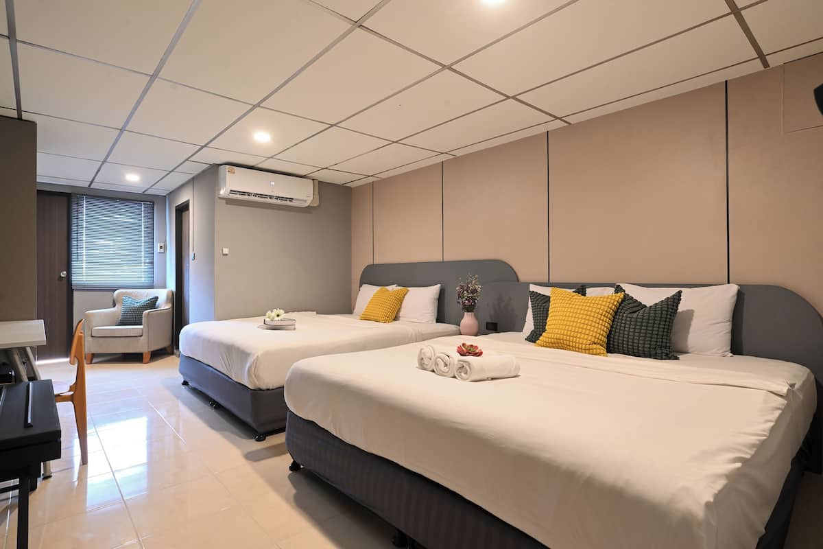 A hotel room with two beds, a desk, and a chair.