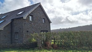 A stone building with a sloped roof, multiple windows, and a small door.