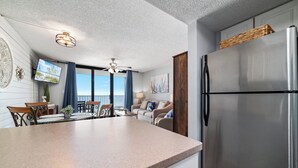 A modern kitchen with a stainless steel refrigerator, a dining area with a table and chairs, and a ceiling fan. - Sunswept 705  Beach Front - King Bed -  POOL - Orange Beach  (Orange Beach)