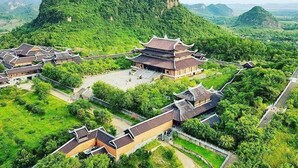 Un ensemble architectural chinois traditionnel composé de plusieurs bâtiments dotés de toits à plusieurs niveaux et entouré d’une végétation luxuriante.