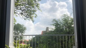 Un balcon donnant sur des arbres et un ciel nuageux.