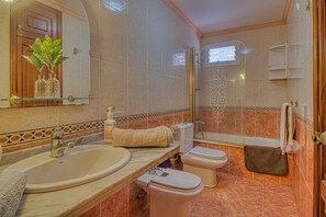 Enjoy a refreshing shower in the bathroom with a curved sink, separate toilet, and glass door.