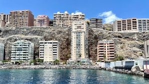 Un paisaje urbano costero con edificios altos, una costa rocosa y agua azul cristalina.