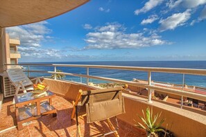 Enjoy the ocean view from this balcony with a chair and table.
