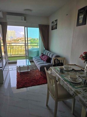 Departamento Deluxe, balcón, vista al mar | Área de sala de estar | Televisión de pantalla plana 