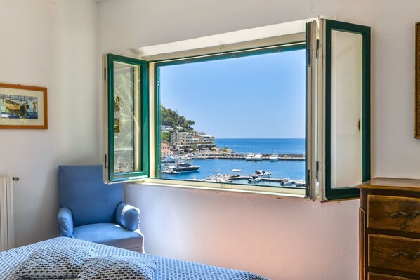 A room with a large window overlooking a marina and buildings.
