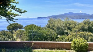 Un paysage côtier offrant une vue dégagée sur la mer, une montagne lointaine et une clôture au premier plan.