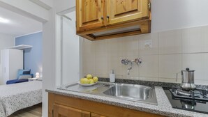 A kitchen with granite countertops, wooden cabinets, a stainless steel sink, and a coffee maker. - Residenza - Le Nereidi - Maia (Capoliveri)