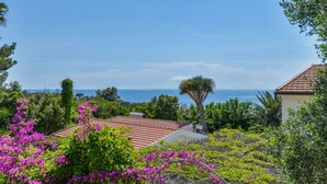 A coastal property with a view of the sea, surrounded by lush greenery and flowering plants. - Residenza - Le Nereidi - Maia (Capoliveri)
