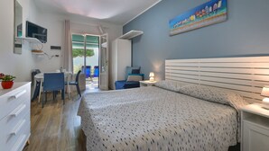A bedroom with a bed, a desk, chairs, a TV, and a painting on the wall. - Residenza - Le Nereidi - Maia (Capoliveri)