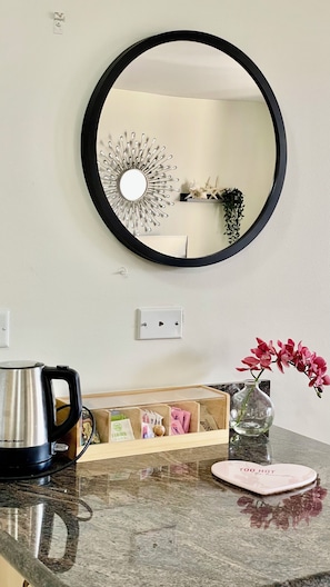 A kitchen with a round mirror, a kettle, a vase with flowers, and a countertop organizer. - 1Bd Condo Diamond head & Ocean view Free Parking Free Amenities Walk to Beach (Honolulu)