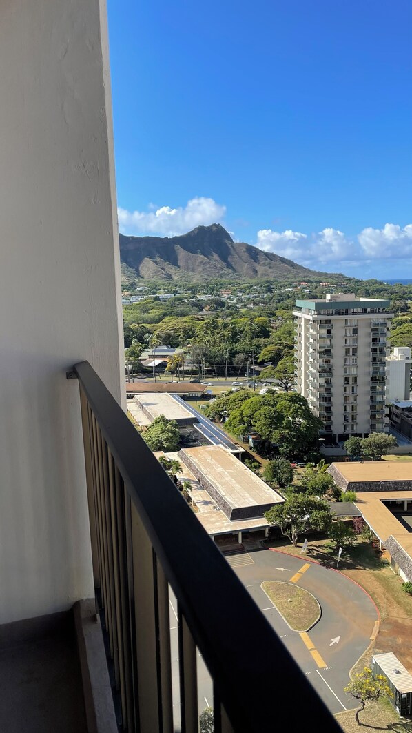 A balcony with a view of a mountain, buildings, and a parking area.
