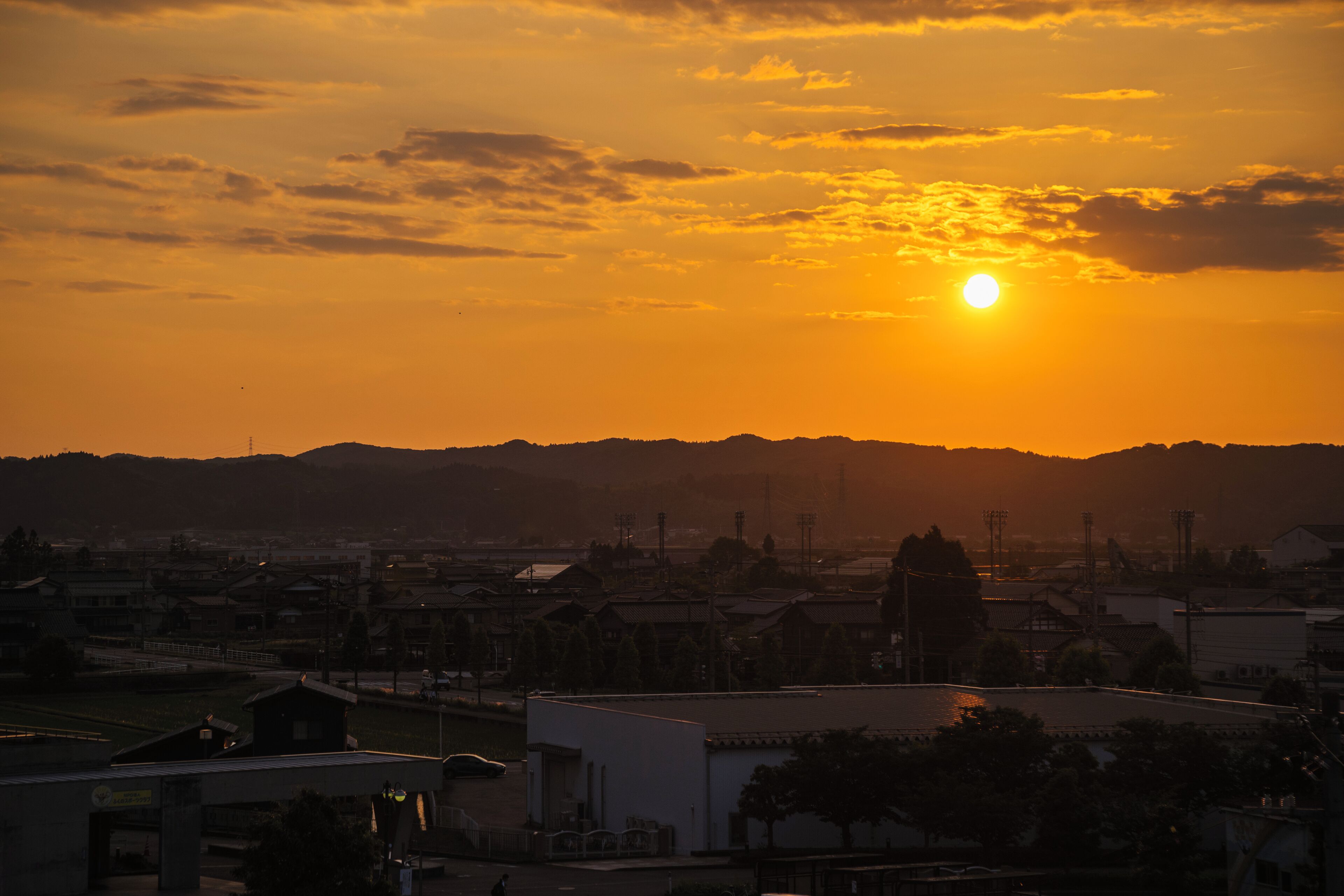 A sunset over a cityscape with buildings and a distant mountain range.