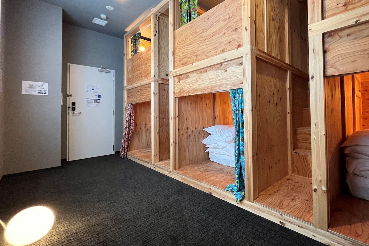A hotel room with a bunk bed, a door with a sign, and a carpeted floor.