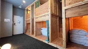 Une chambre d’hôtel avec des lits superposés, un sol recouvert de moquette et une porte avec une pancarte.