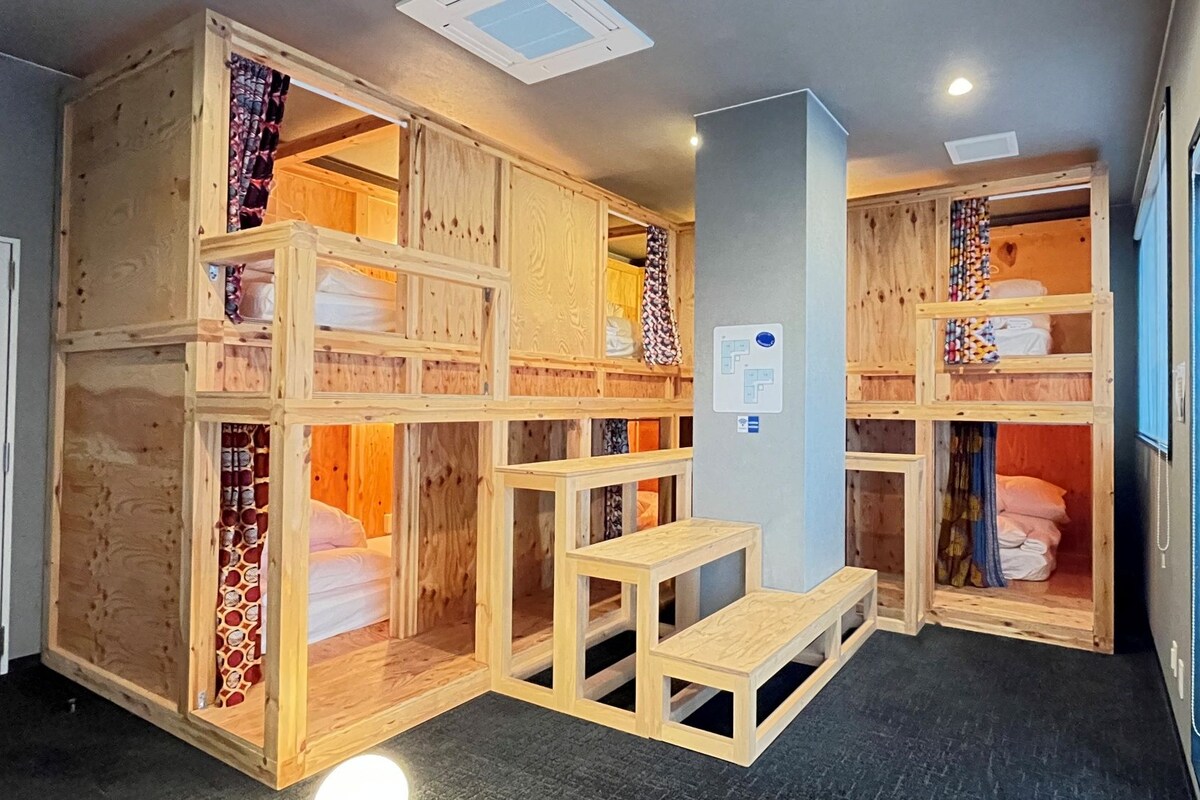 A room with a bunk bed, a small table, and a wardrobe.
