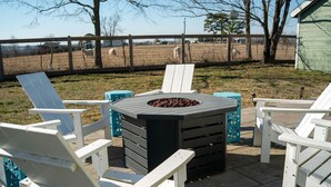 Eine Terrasse mit Adirondack-Stühlen und einem Feuerkorb.