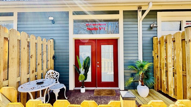 A wooden fence, a red door, and a white chair outside a building.