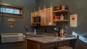 A kitchen with wooden cabinets, a built-in microwave, a coffee maker, and a sign for Tito's Handmade Vodka.